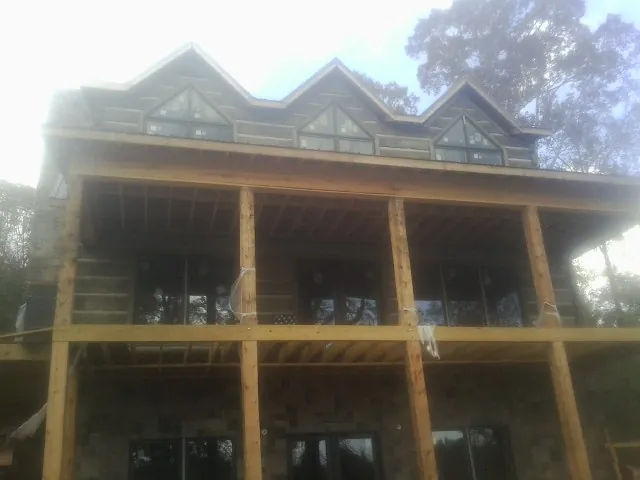 Dormers and porch framing on a large log home under construction — Roof Coating work by our crew in Lannon