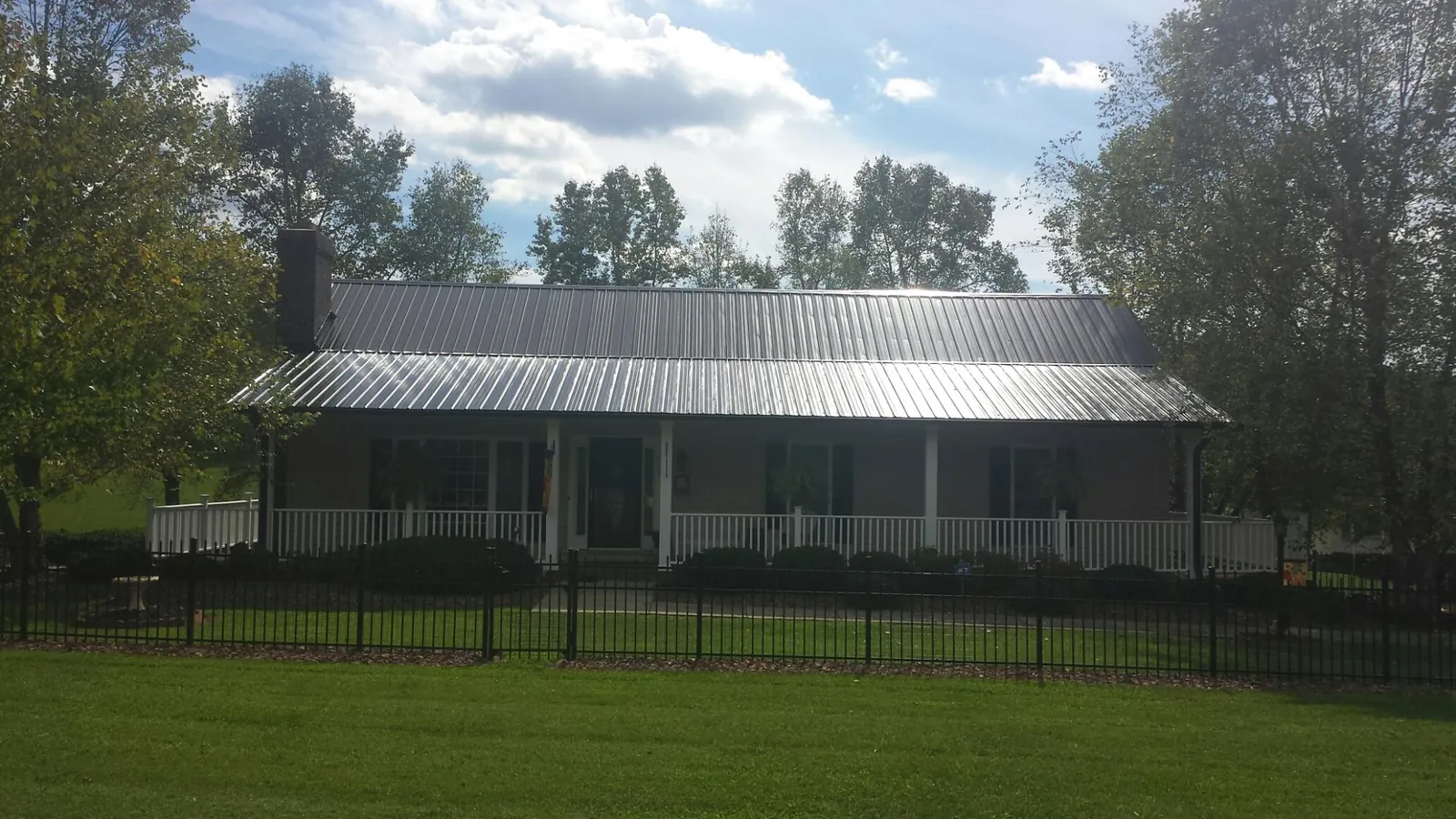 Gray metal roof on a brick ranch with a full width front porch — Gutter Guard Installation work by our crew in Lannon