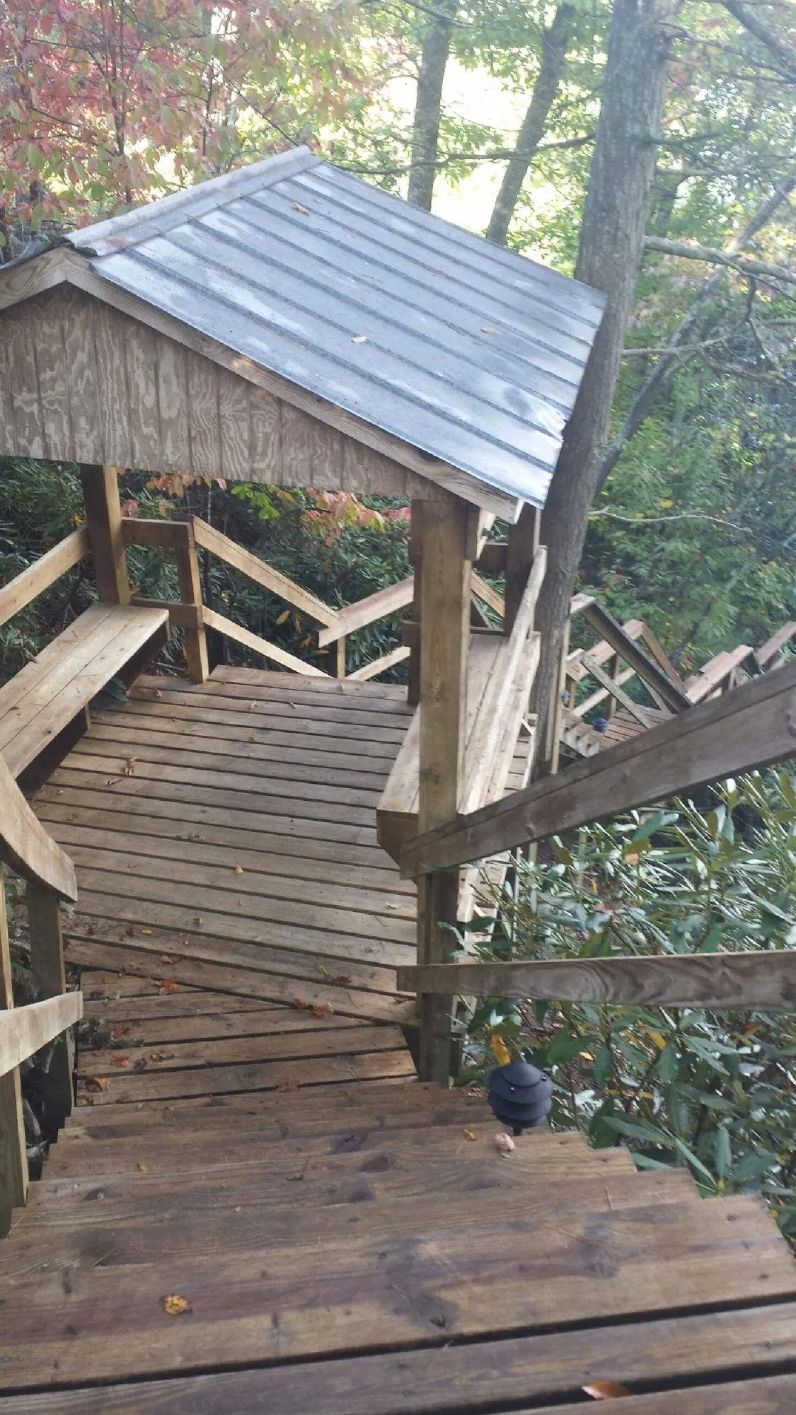 Metal roofed shelter over wooden steps on a wooded walkway — Skylight Repair & Installation work by our crew in Lannon