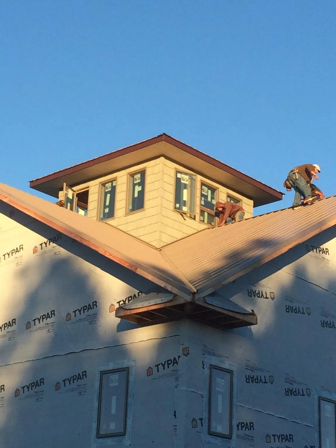 Roofers working around a rooftop cupola on a new metal roof at sunset — Roof Waterproofing in Lannon by Roofing Brothers